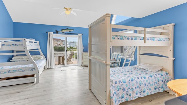 A bedroom with two bunk beds, a ceiling fan, and a view of the outdoors.