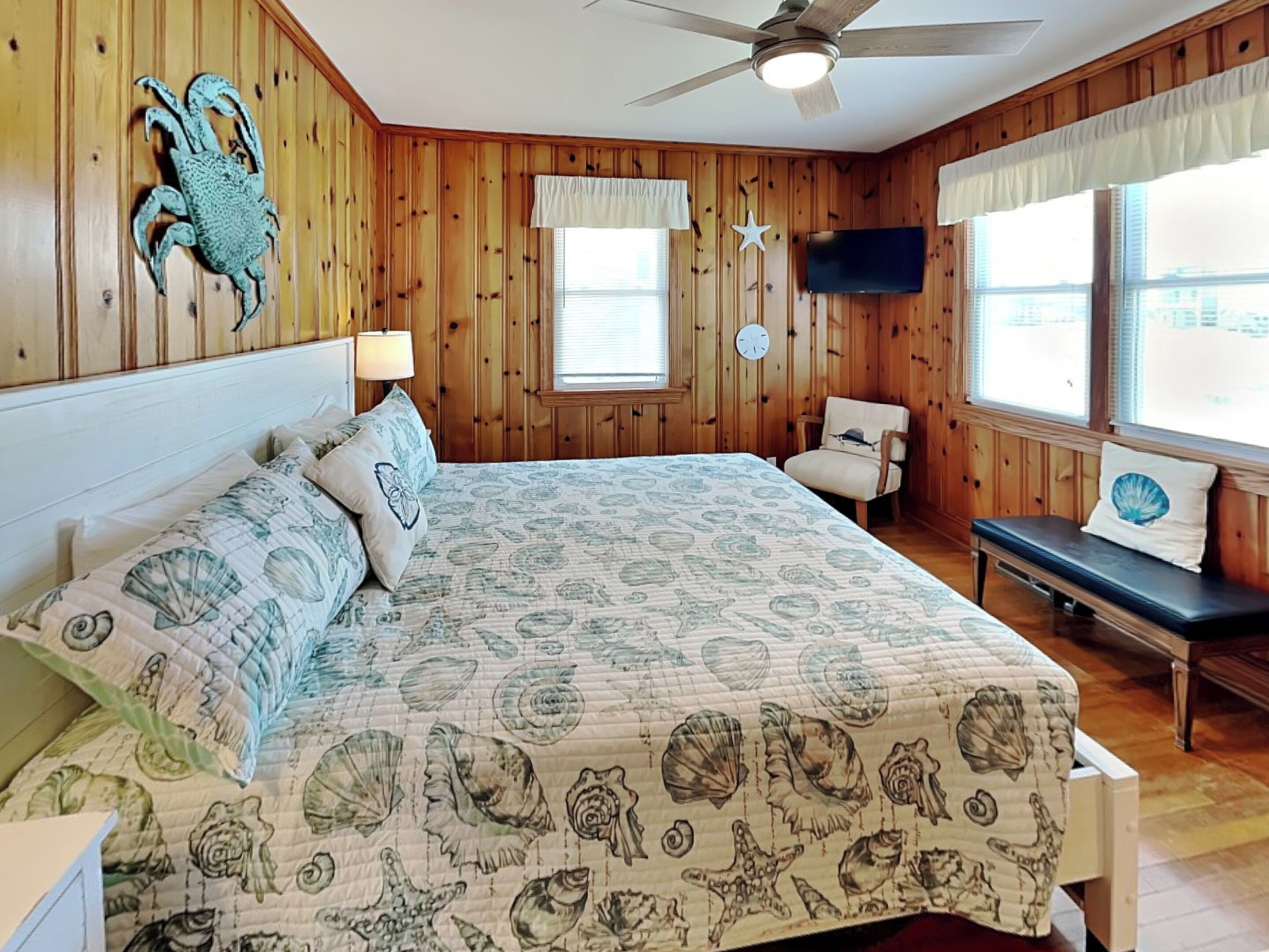 A bedroom with a bed, a chair, a television, and a window with blinds.