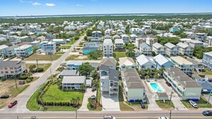 Zona residencial con varias casas de dos pisos, una piscina y vista despejada del océano.
