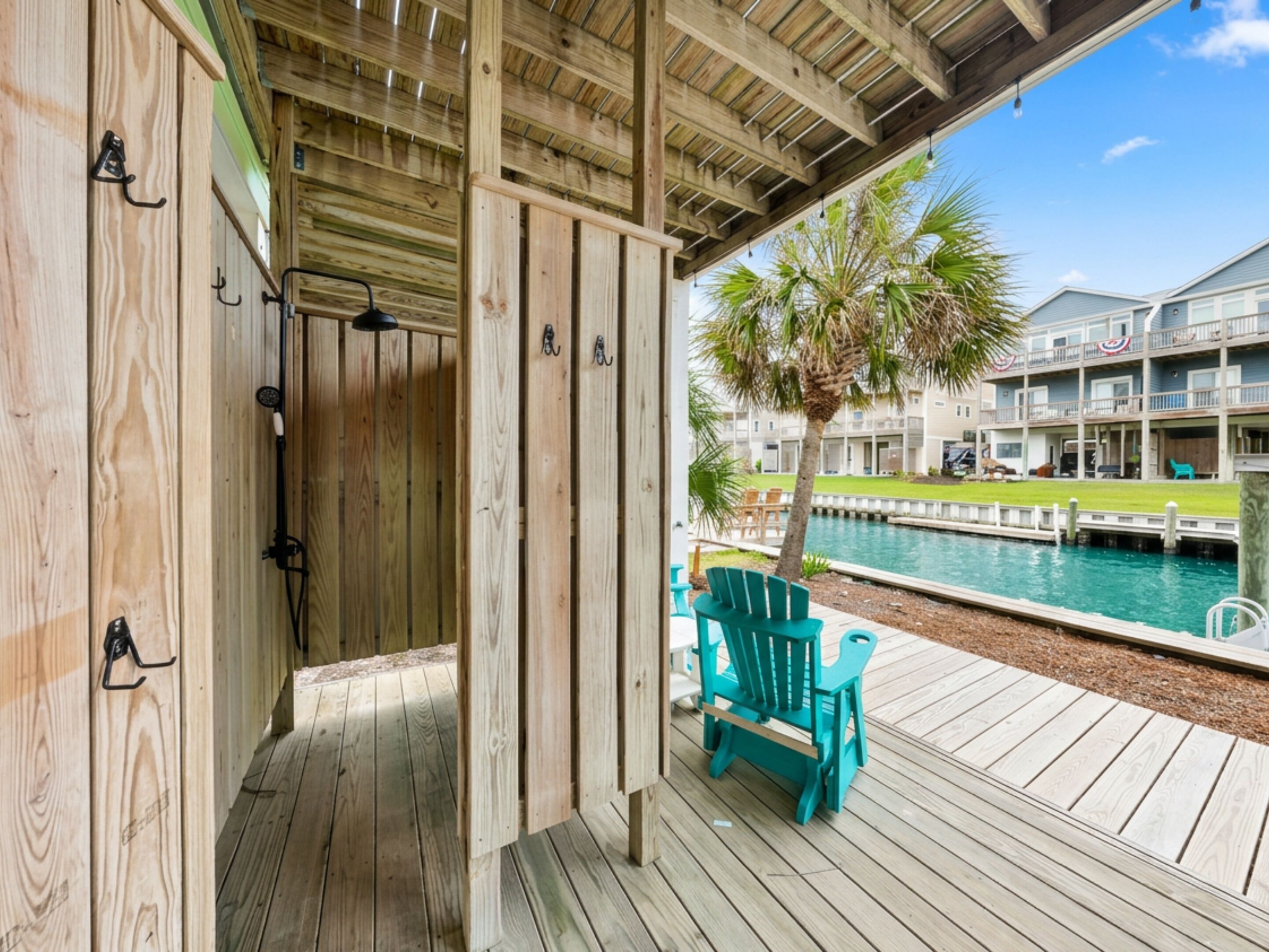 A wooden deck with a pool, a palm tree, and a building in the background.