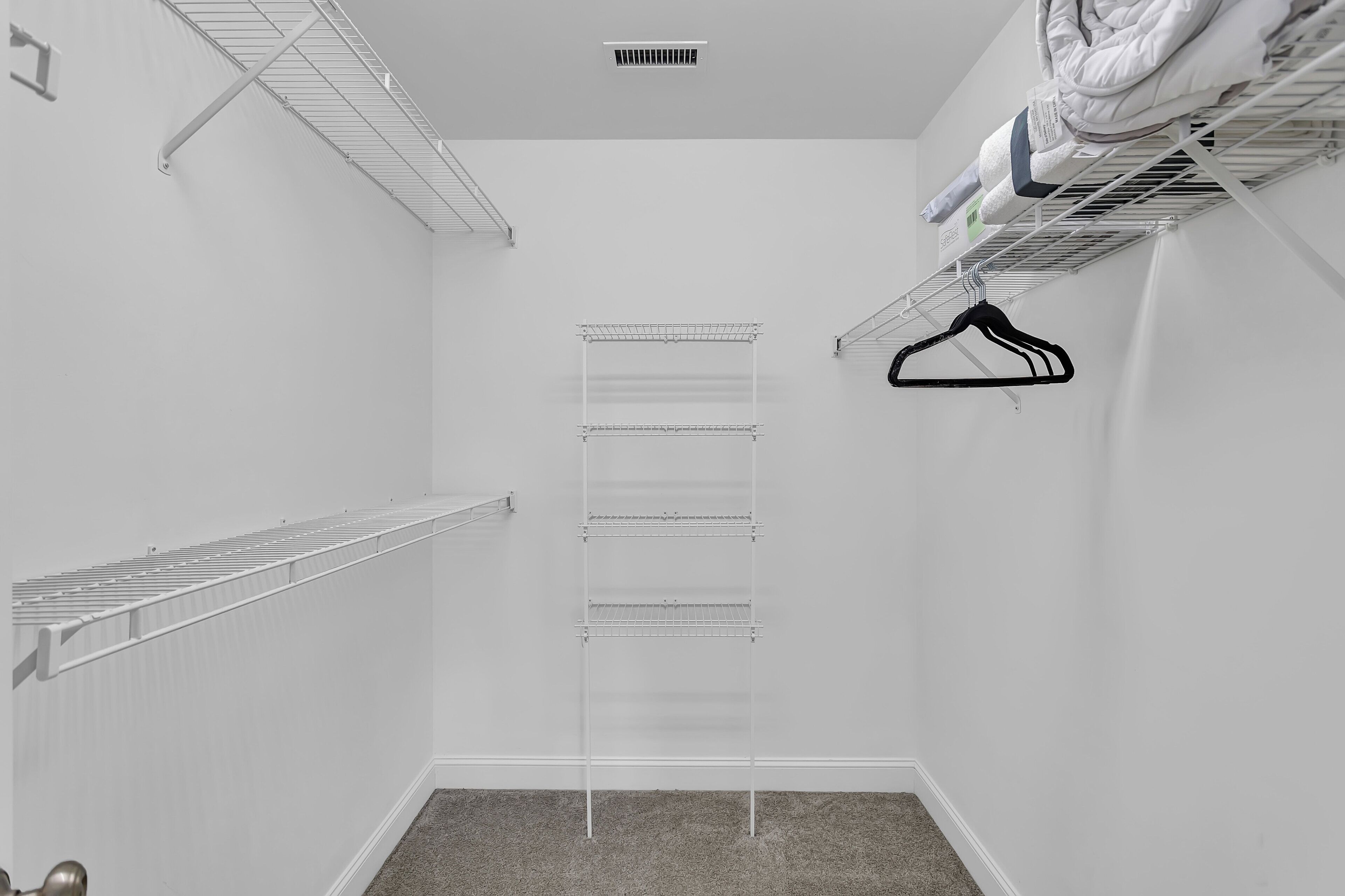 A walk-in closet with metal shelving units, a radiator, and a ceiling vent.