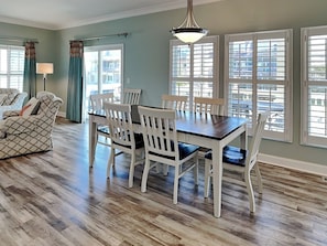 A dining area with a table and chairs, a sofa, and a lamp.