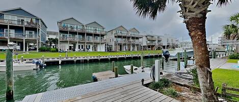 A waterfront property with a dock, a grassy area, and a building with multiple balconies.