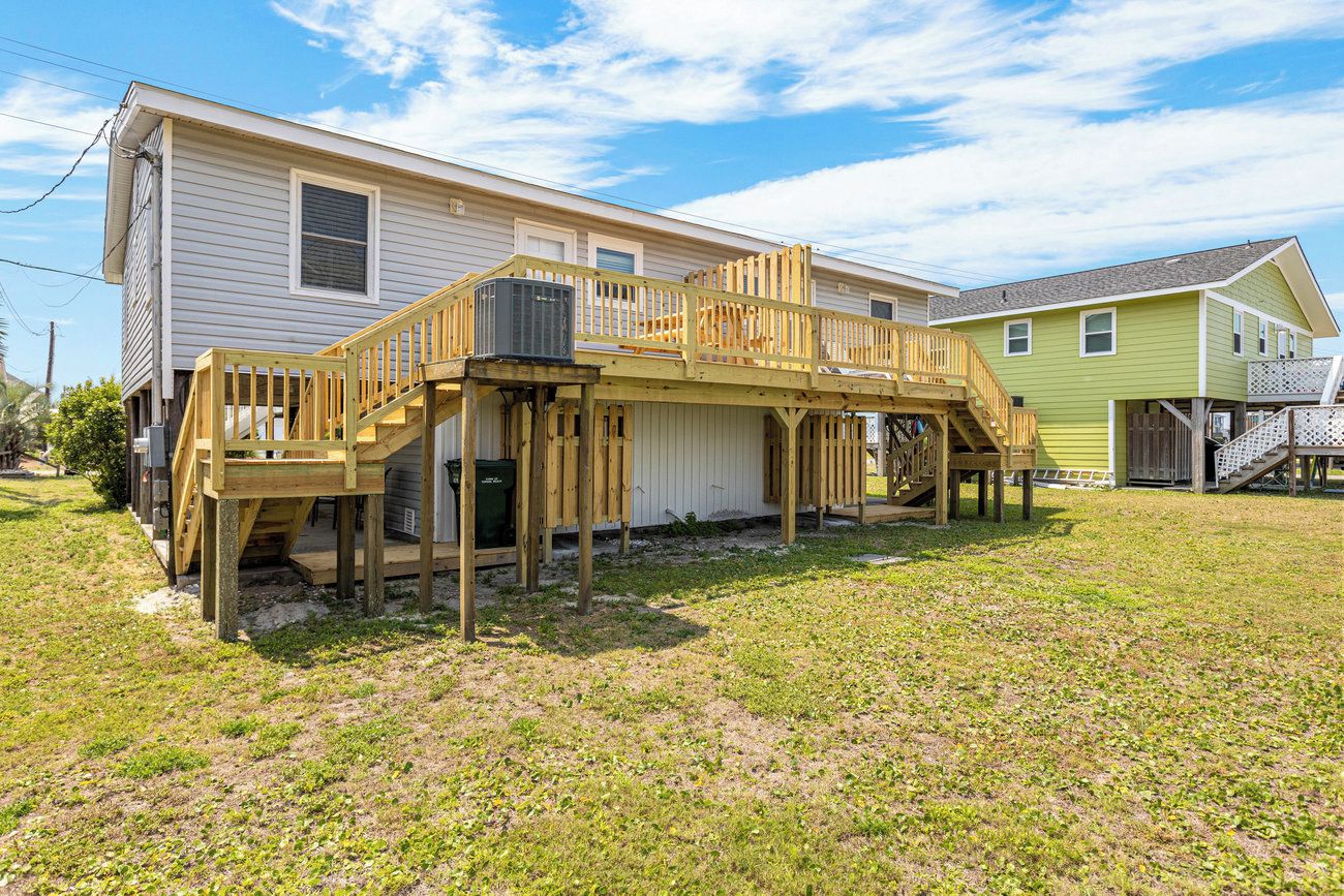 A two-story house with a wooden deck and stairs leading to the second floor.