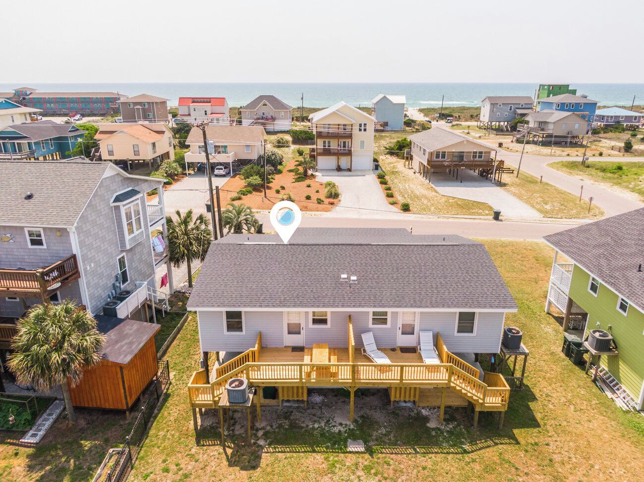 Uma área residencial à beira-mar, com uma casa que tem varanda e um pequeno jardim.