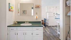 A compact kitchen with white cabinets, a green countertop, and a white refrigerator. - Catch A Wave by Topsail Realty (Holly Ridge)