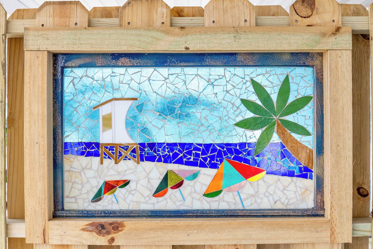 A mosaic artwork with a beach scene, including a palm tree and geometric shapes.