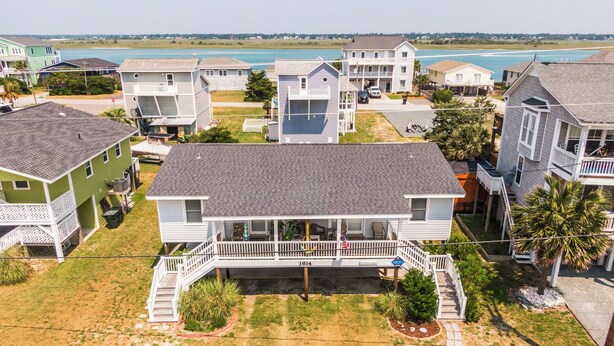 Um imóvel à beira-mar com várias casas, varanda coberta e gramado de areia.