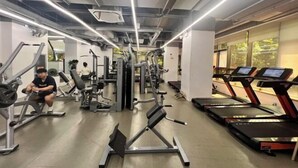 Kuntosali, jossa on juoksumattoja, painonnostolaitteita ja henkilö soutulaitteessa.
