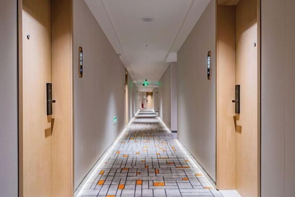 A hotel hallway with wooden doors, a patterned floor, and a long corridor. - Brook Hotel (Hangzhou)