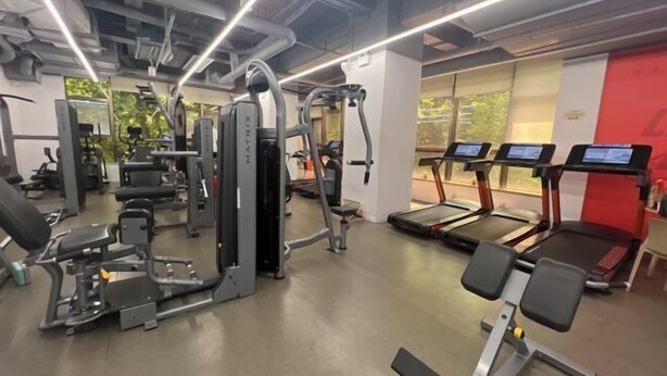 A gym with various exercise equipment, including treadmills and weight machines. - Brook Hotel (Hangzhou)