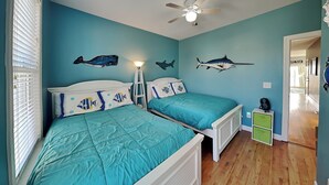 A room with two beds, a ceiling fan, and wall decorations of fish. - Lucky Ducky by Carolina Retreats (Carolina Beach)