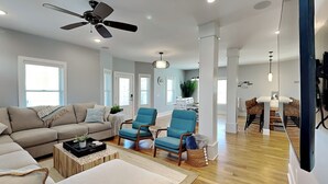 A spacious living room with a sofa, armchairs, a coffee table, and a dining area in the background. - Beaches Be Crazy by Carolina Retreats (Carolina Beach)