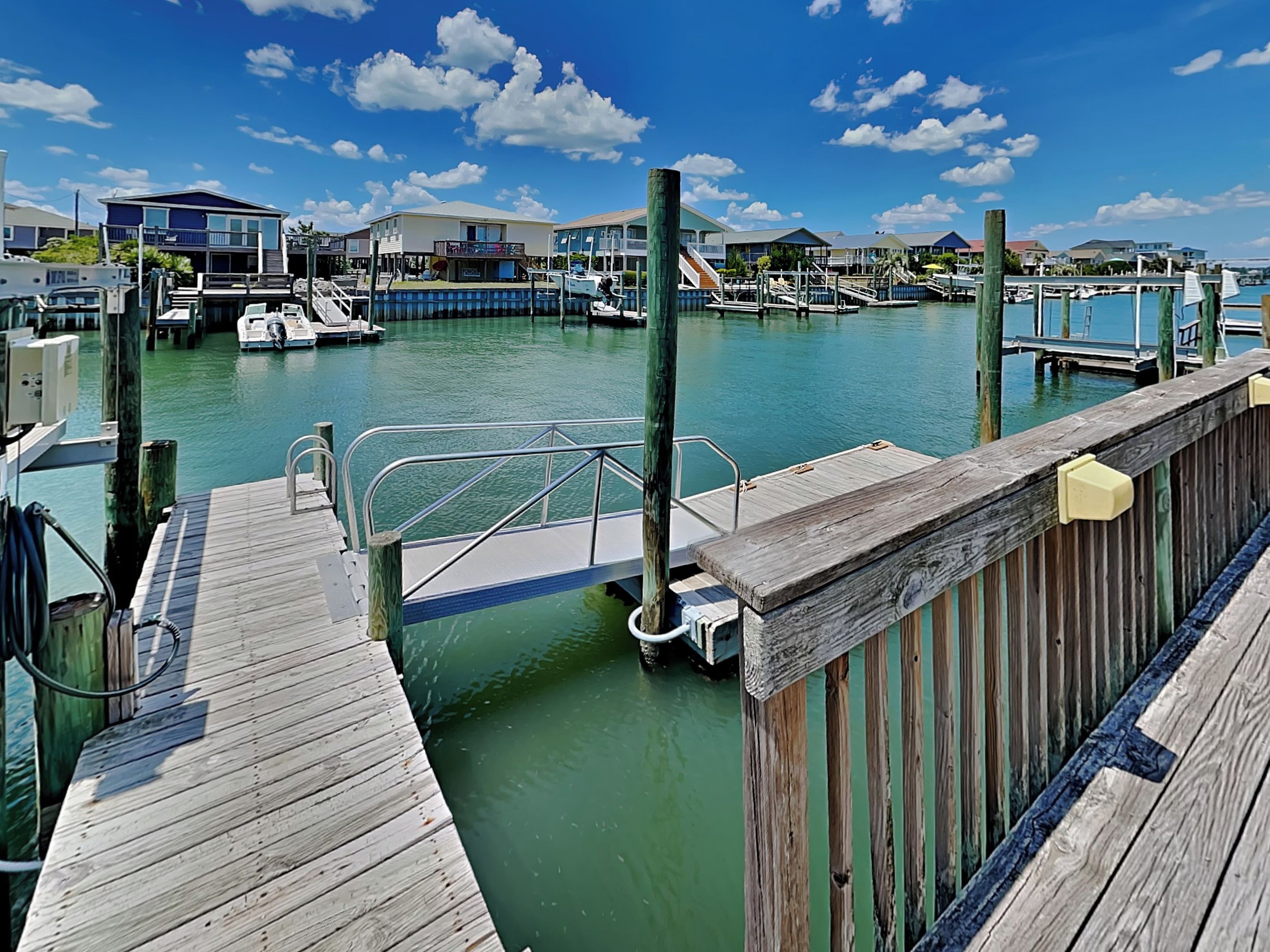 A marina with docked boats, wooden walkways, and buildings in the background.