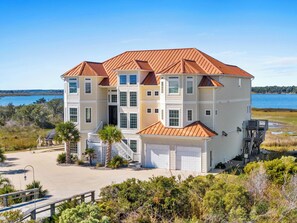 A multi-story house with a red roof, a garage, and a view of the water. - Permuda Private Island by Topsail Realty (Sneads Ferry)