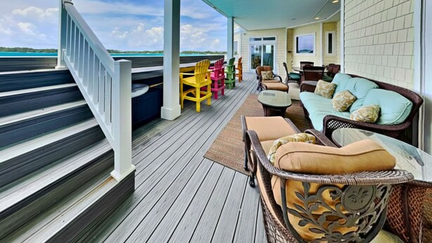 A covered outdoor deck with a wooden staircase, outdoor furniture, and a view of the ocean. - Permuda Private Island by Topsail Realty (Sneads Ferry)