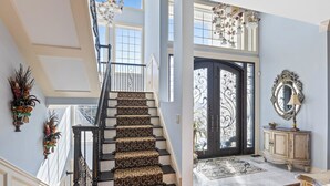 A grand staircase with patterned carpet, a black railing, and a decorative mirror on the wall. - Permuda Private Island by Topsail Realty (Sneads Ferry)