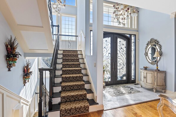 A grand staircase with patterned carpet, a black railing, and a decorative mirror on the wall. - Permuda Private Island by Topsail Realty (Sneads Ferry)