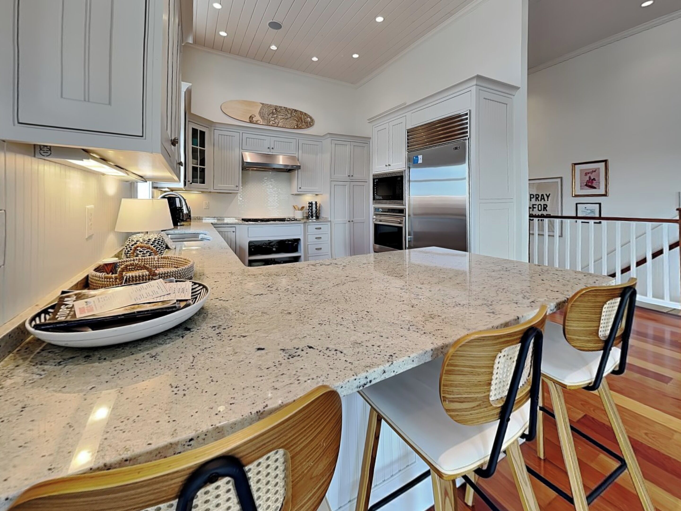 A modern kitchen with white cabinetry, a granite countertop, and a stainless steel refrigerator.