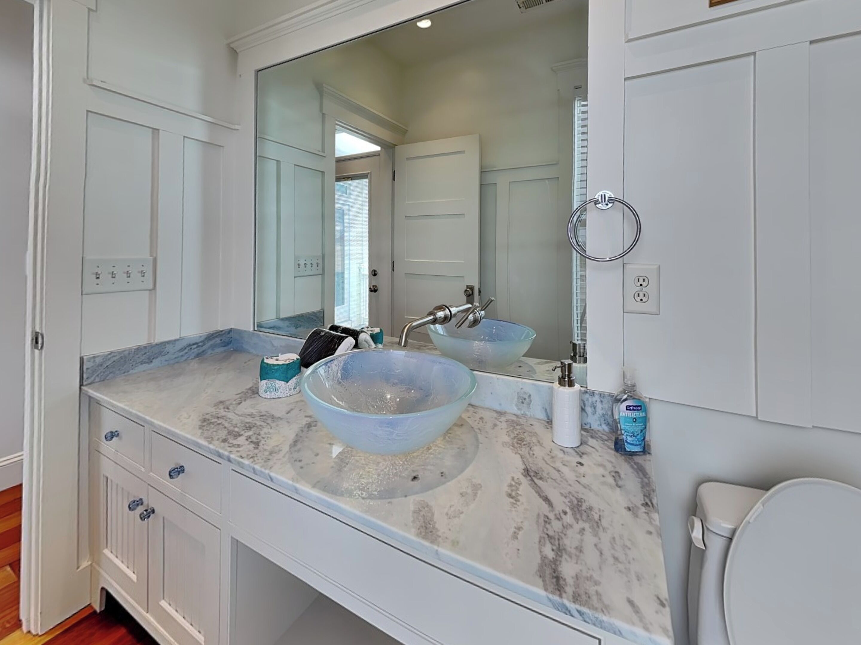 A bathroom with a large mirror, two sinks, and a toilet.