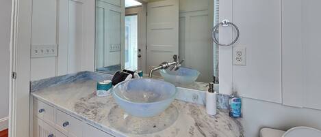 A bathroom with a large mirror, two sinks, and a toilet.