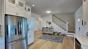 A modern kitchen with stainless steel appliances, white cabinetry, and a wooden floor. - Pelican Landing by Topsail Realty (Sneads Ferry)