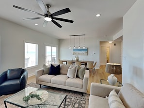 A spacious living room with a ceiling fan, a dining area with a view, and a kitchen with a round table. - Pelican Landing by Topsail Realty (Sneads Ferry)