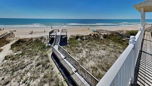 Vista a la playa desde un balcón con terraza de madera y vista al océano.