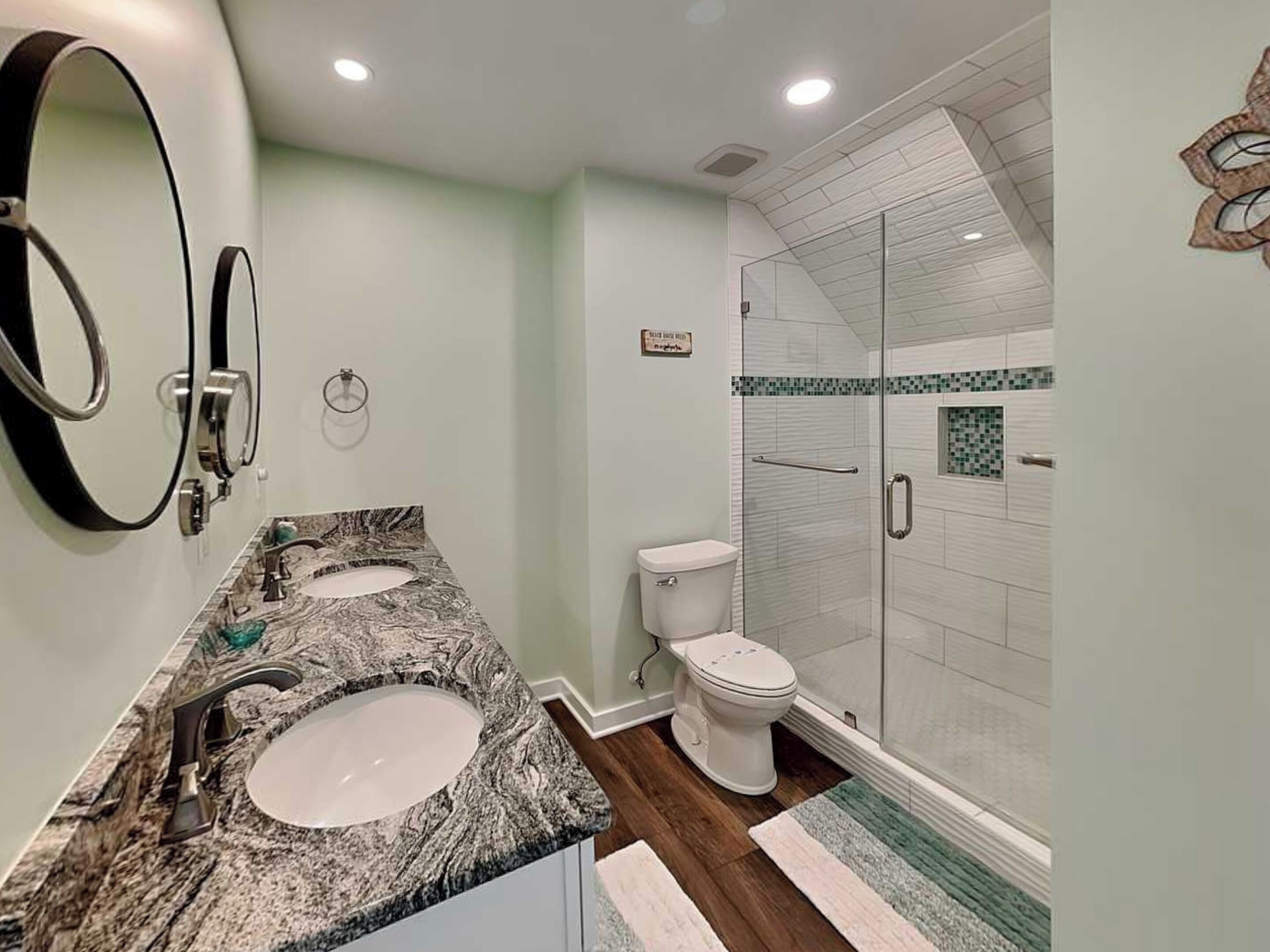A bathroom with two sinks, a toilet, and a glass shower enclosure.