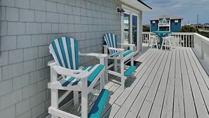 A wooden deck with two Adirondack chairs and a small table. - Salty Seahorse by Topsail Realty (Sneads Ferry)
