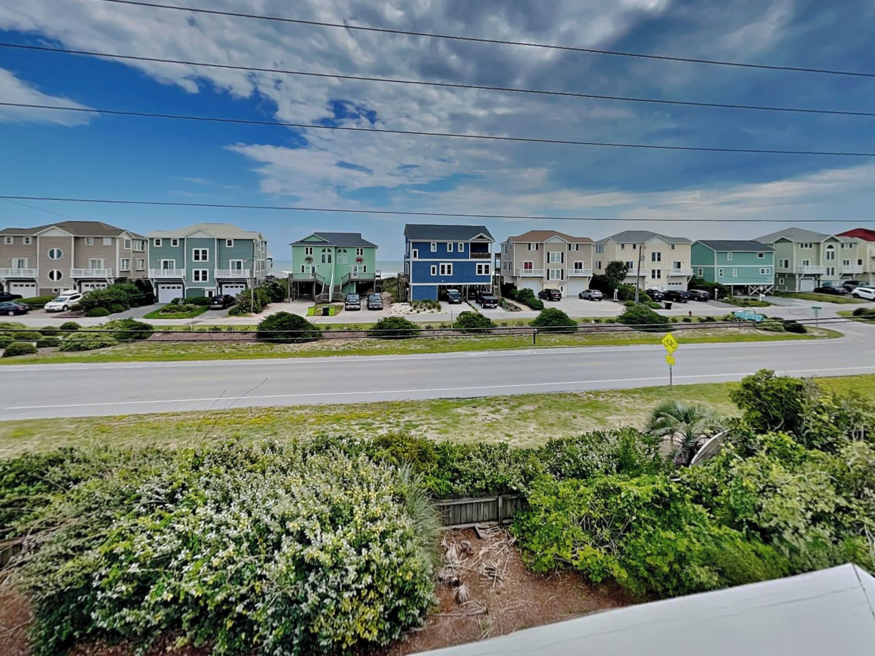 A row of townhouses with a road in the foreground and a clear sky.