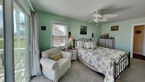 A bedroom with a bed, a nightstand, a dresser, a chair, a window with blinds, and a ceiling fan. - Salty Seahorse by Topsail Realty (Sneads Ferry)