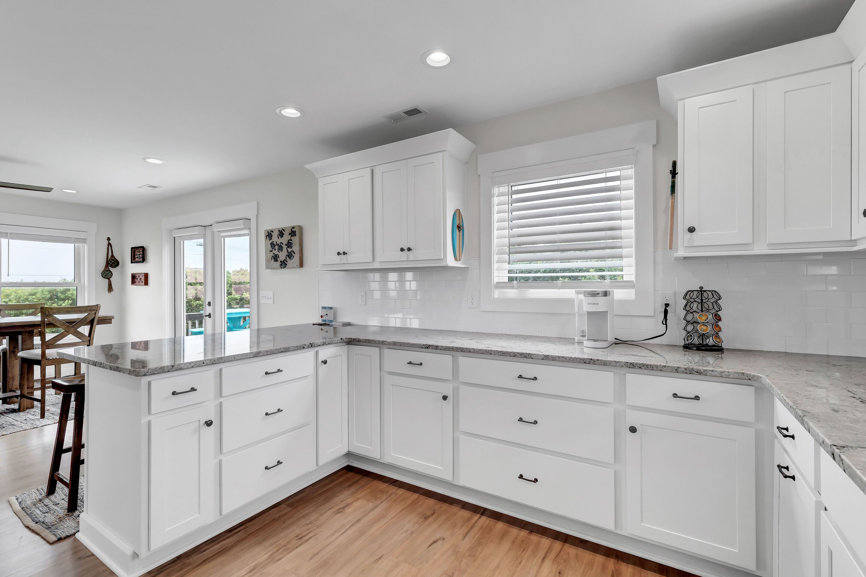 A modern kitchen with white cabinetry, a marble countertop, and a large island.