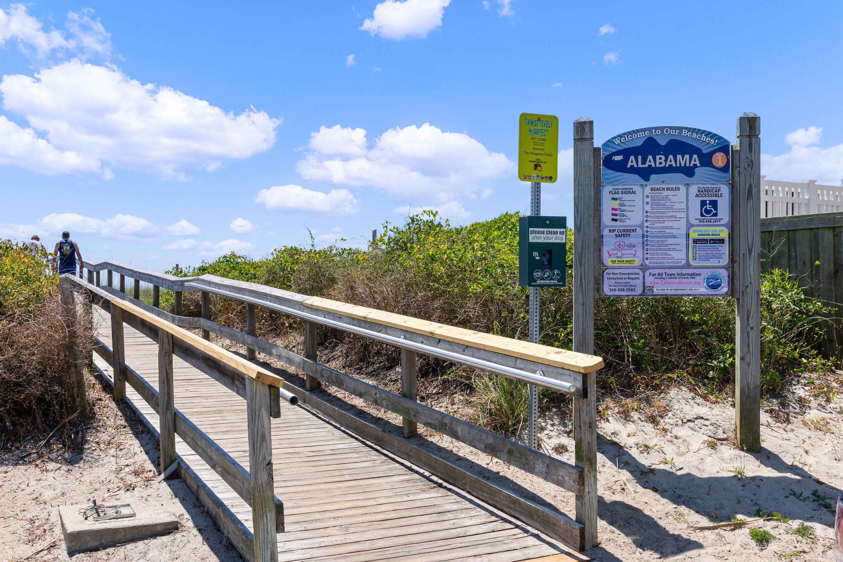A wooden boardwalk leading to a beach with informational signs.
