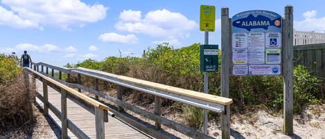 A wooden boardwalk leading to a beach with informational signs.