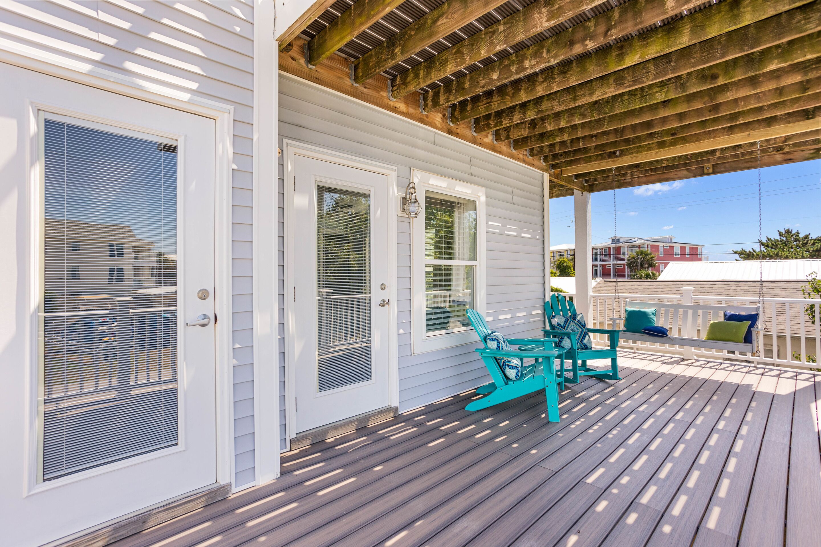 A covered porch with a wooden ceiling, white siding, and a wooden deck.