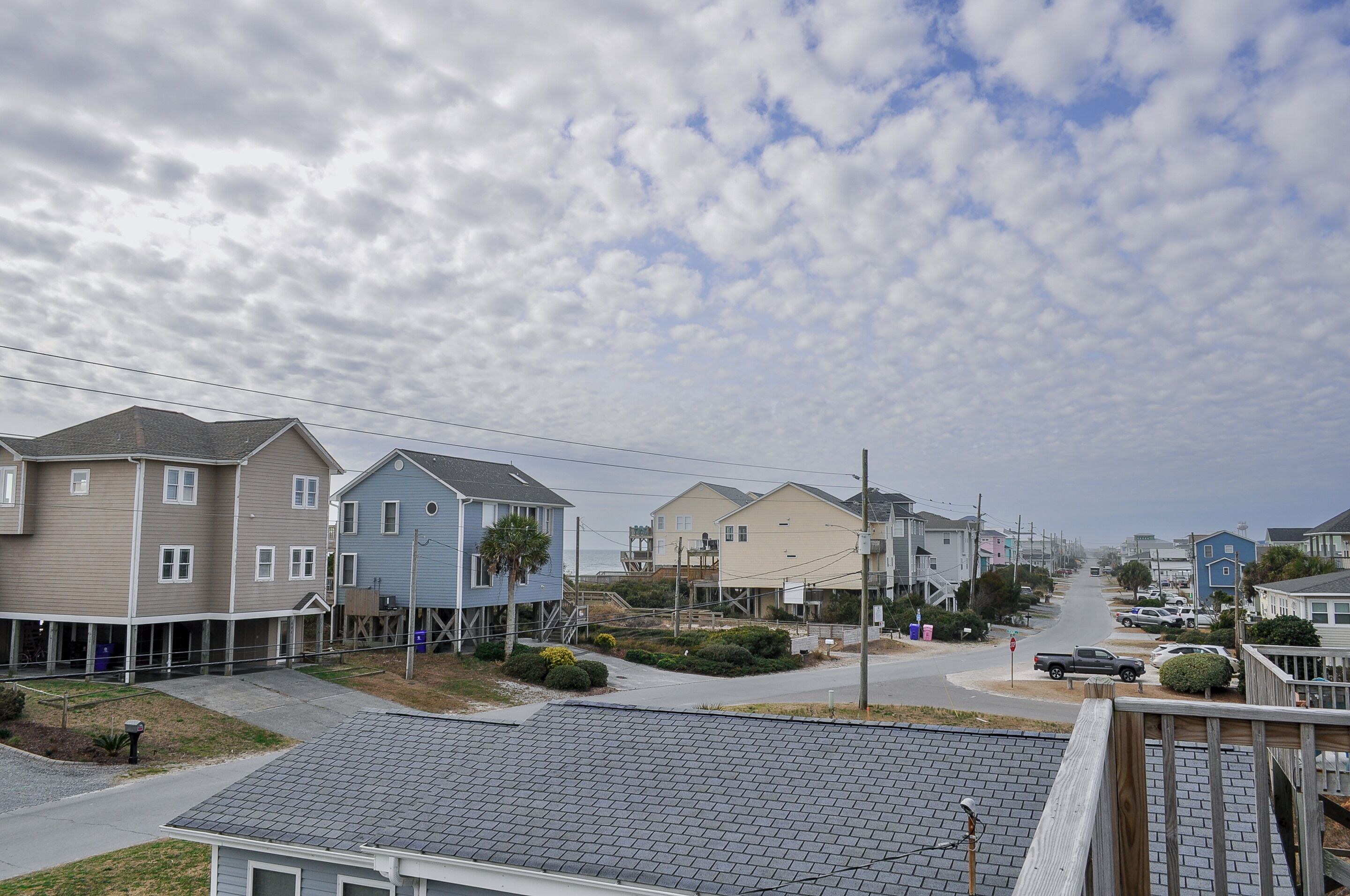 A residential street with houses, a clear sky, and a visible road.