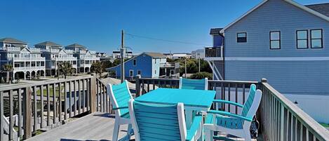 A wooden deck with a table and chairs, overlooking a residential area with houses.