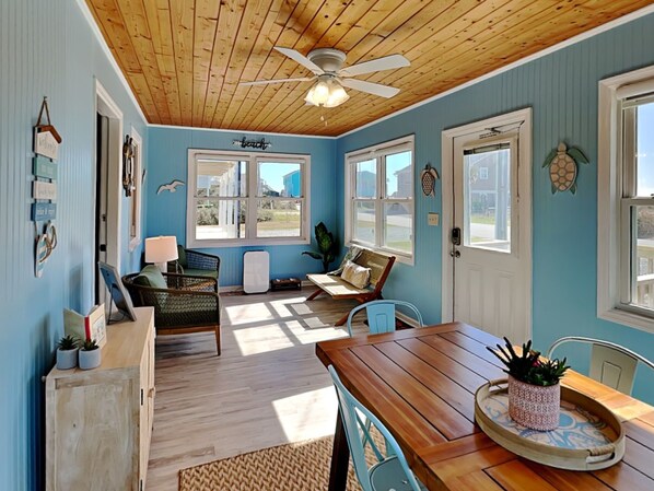 Une pièce avec un plafond en bois, un ventilateur de plafond, une table à manger avec des chaises, une fenêtre et une porte.