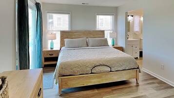 A bedroom with a wooden bed, two bedside tables with lamps, a ceiling fan, and a window with blinds.