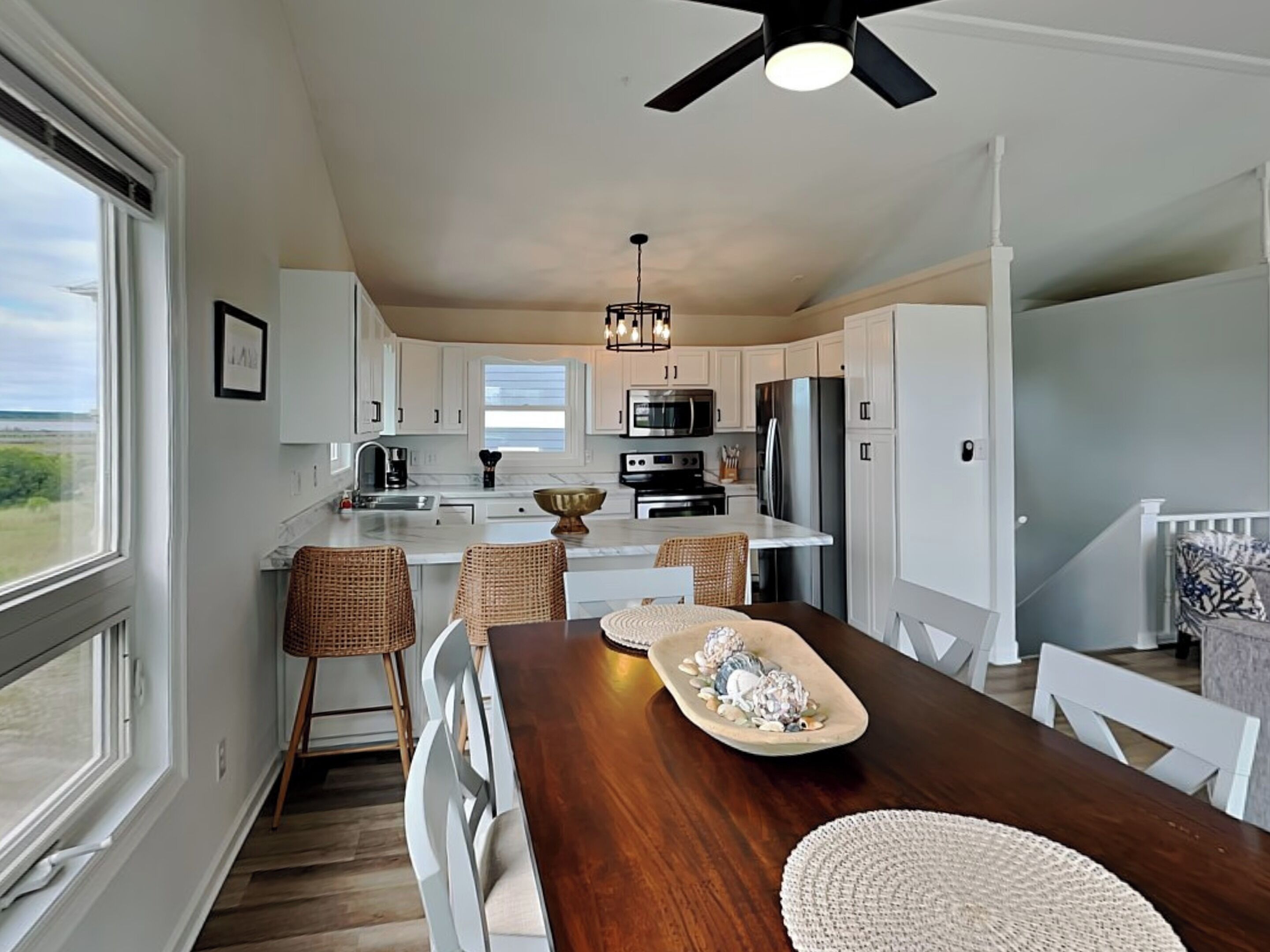 A modern kitchen with white cabinetry, a central island, and a dining area with a wooden table and chairs.