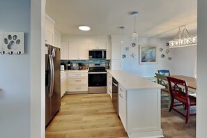 Una cocina moderna con armarios blancos, electrodomésticos de acero inoxidable y piso de madera.