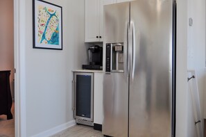 Une cuisine équipée d’un réfrigérateur en acier inoxydable, d’une machine à café et d’un petit réfrigérateur situé en dessous.