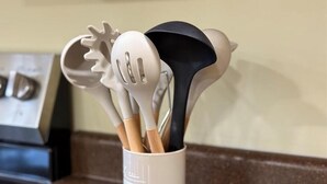 A white utensil holder with various kitchen tools.