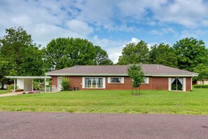Een gelijkvloers bakstenen huis met een overdekte veranda, voortuin en heldere lucht.