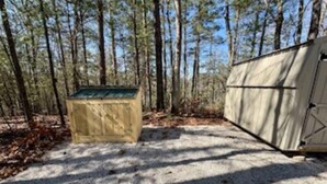 A tented camping area with a gravel path, surrounded by tall trees. - Ultimate Climber's Getaway (Rogers)