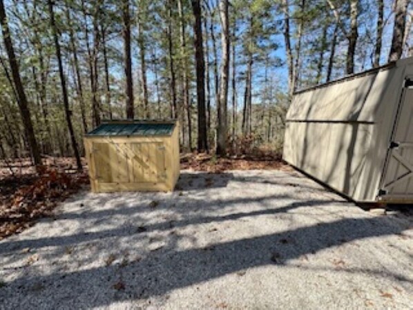 A tented camping area with a gravel path, surrounded by tall trees. - Ultimate Climber's Getaway (Rogers)