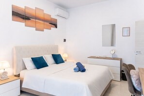 A hotel room with a bed, bedside lamps, a dresser, a mirror, and a wall-mounted air conditioner.