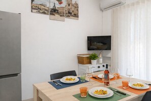 Ein Essbereich mit einem Tisch für zwei Personen, einem Fernseher darüber und einem Kühlschrank zur Linken.