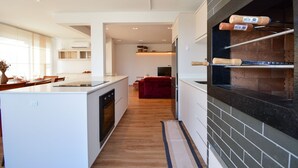A modern kitchen with a central island, a built-in oven, and a brick oven wall. - Cobertura SunClub-300 mtrs da Praia  (Florianopolis)